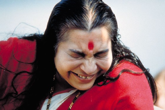 Shri Mataji laughing - showing Sahastrar Chakra - eyes closed, red cardigan