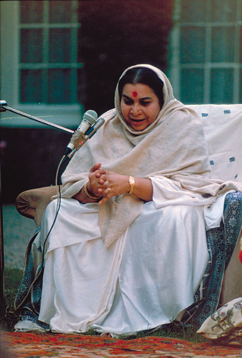 Shri Mataji speaking outside - in armchair, silver sari, cream shawl