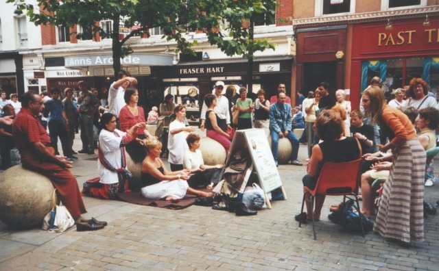 members of the public watch or participate in a street meditation workshop