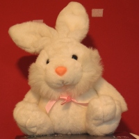 soft toy white rabbit, orange nose and pink bow around neck