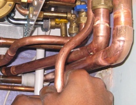 hands grasping copper pipe below boiler