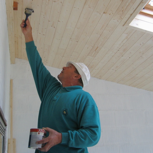 carpenter varnishing softwood ceiling, Velux window top right